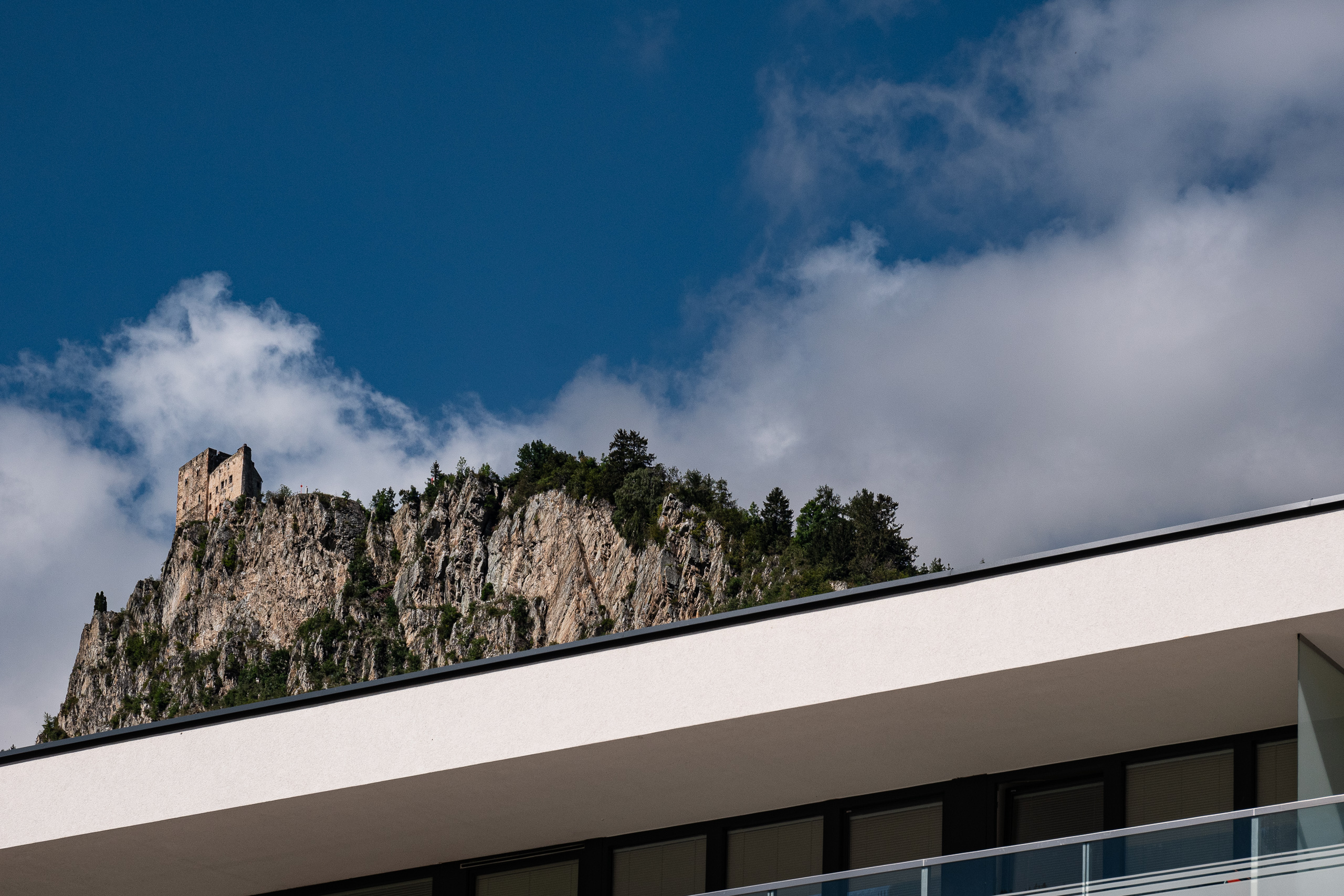 Burgruine auf dem Felsen – darunter ein moderner Neubau
